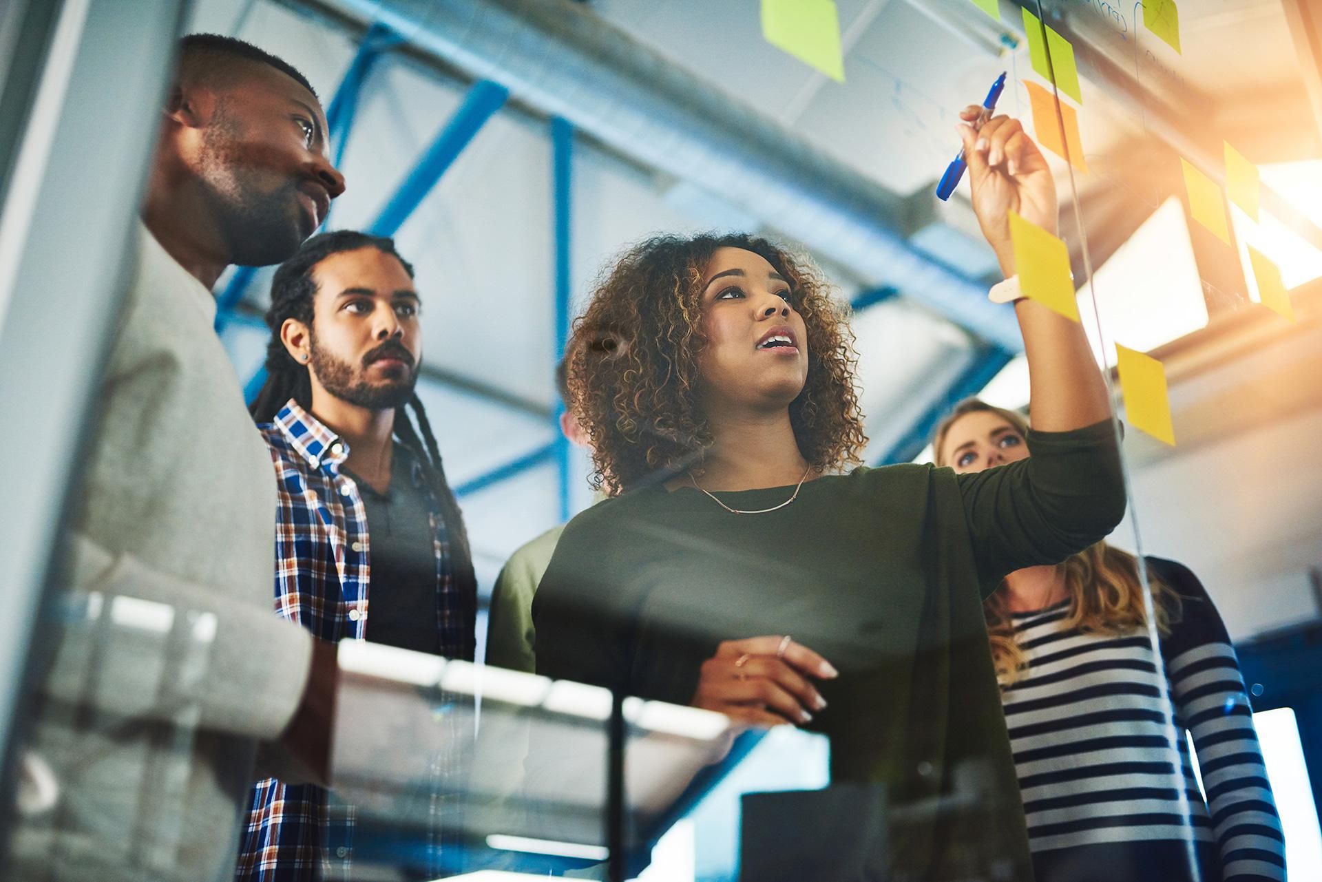 A team of creatives stand together brainstorming their next creative marketing idea