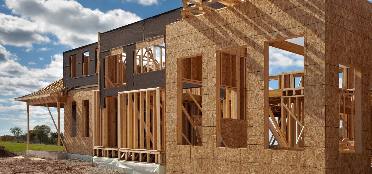 New home under construction with exposed framing and wooden structure against a blue sky.